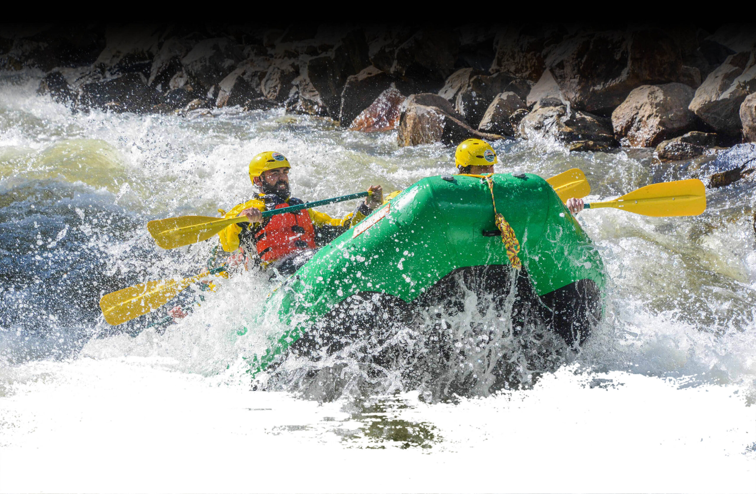 Action shot of rafters powering through white water rapids during a Clear Creek rafting trip with the Colorado Rafting Company on a guided Class IV rafting adventure, surrounded by rugged, Colorado canyon walls.